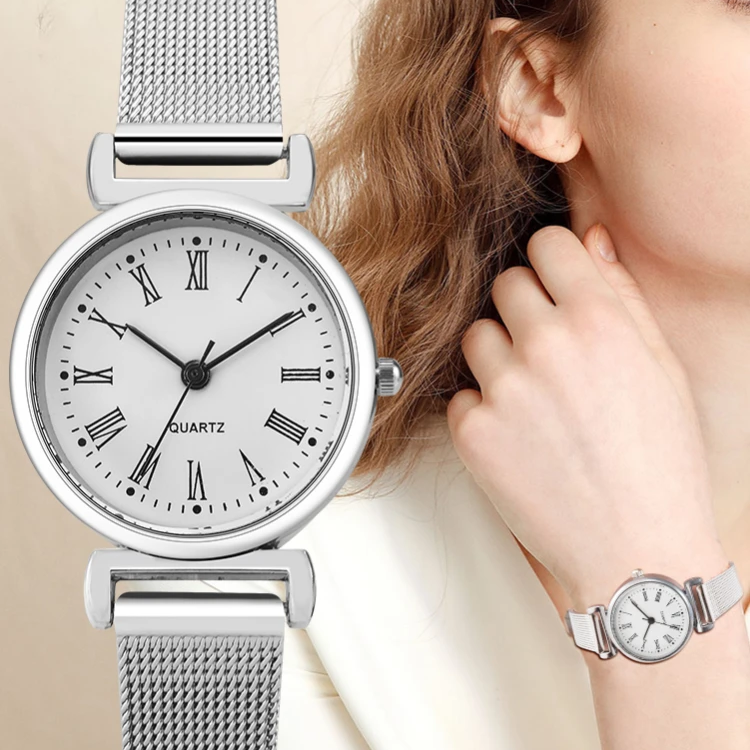 Silver watch with mesh band worn by a person on a beige background